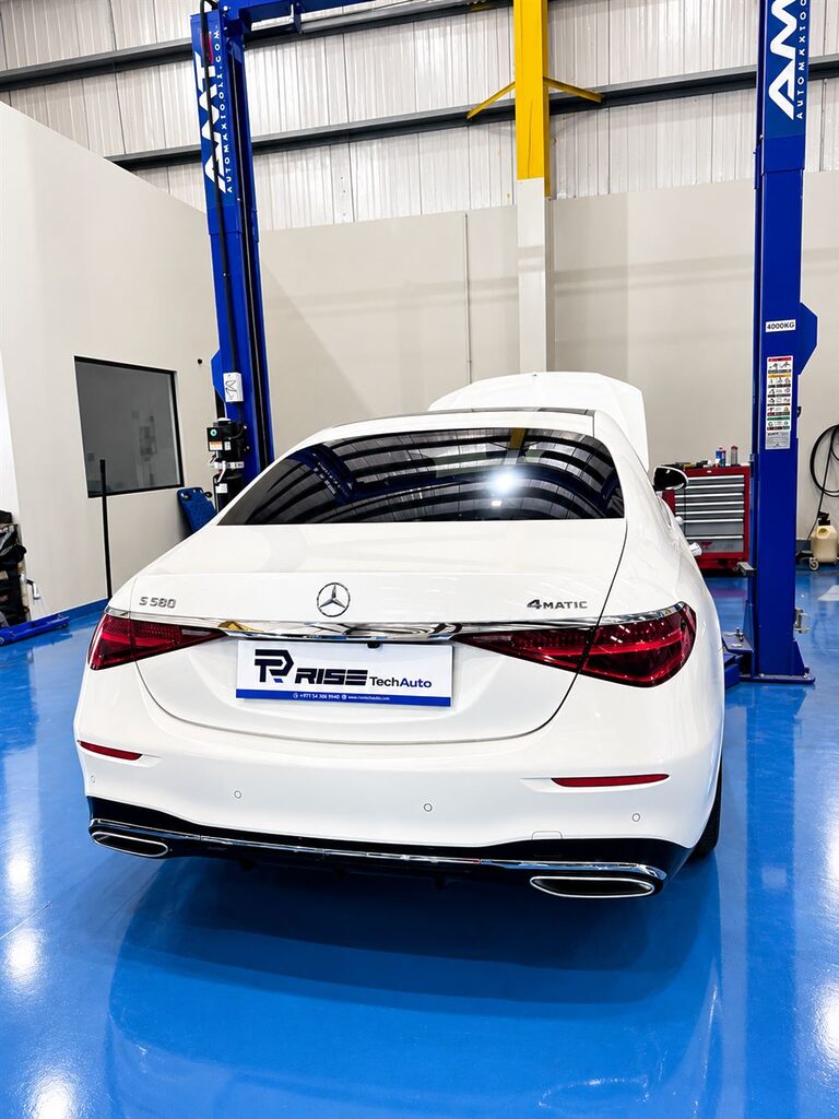 White Mercedes-Benz S-Class beside a car lift in the Rise Tech Auto workshop in Dubai
